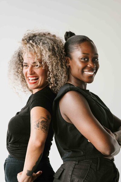 Branded Headshots of two women standing back to back smiling