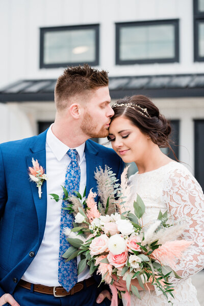 Groom kissing bride on forehead at Crimson Lane Wedding Venue in Ada Ohio