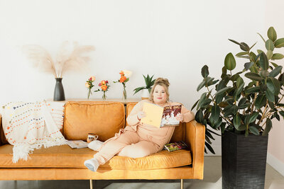 Cinthia Onines sitting down on brown sofa holding a magazine