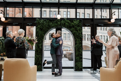 Grooms exchanging first kiss during ceremony at Shinola Hotel Detroit.