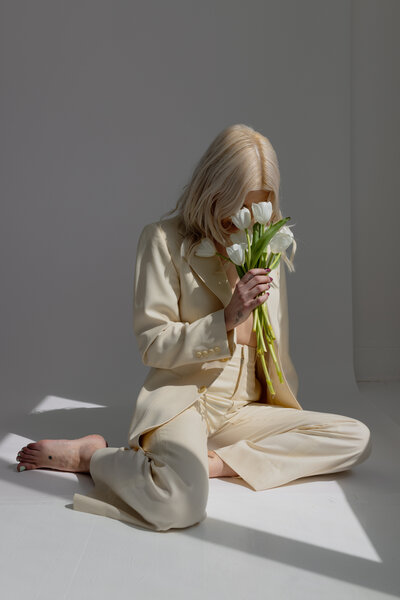 Creative Editorial Portrait of model in studio holding tulips wearing a yellow dress suit