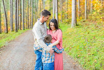 Family embraces together in wood setting for outdoor photoshoot with Tiffany McFalls.