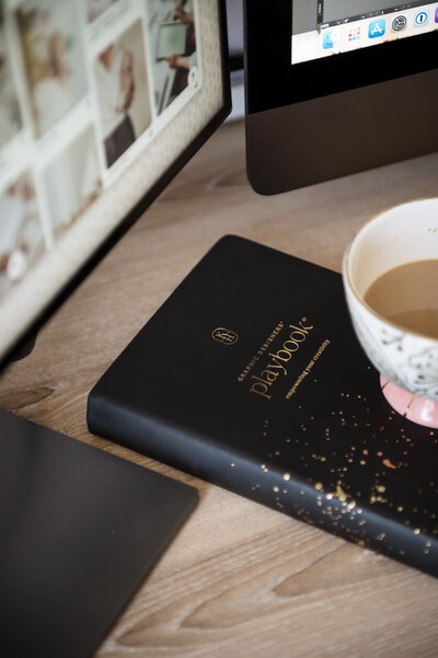 Close up shot of a creative desk showing computers, coffee and a Playbook