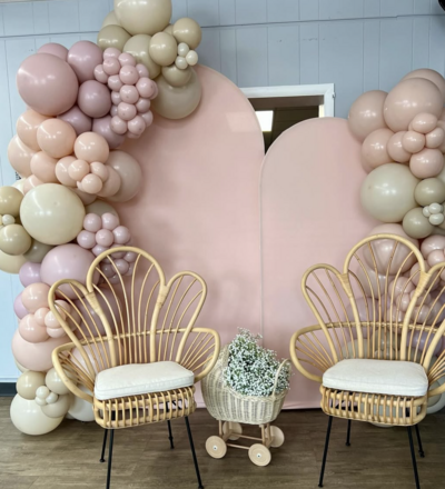 Luxurious pink and gold balloon arrangement with elegant chairs, perfect for baby showers or weddings.