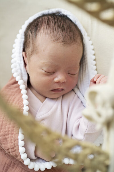 Newborn baby alseep in a moses basket photographed during an at-home newborn photo shoot in Surrey