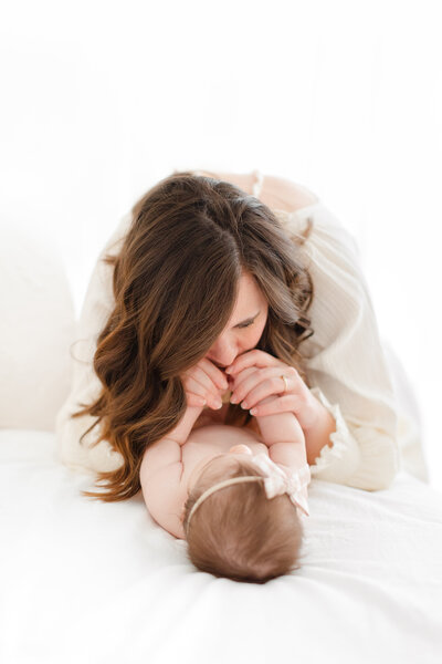 A photo of a mother leaning down kissing her daughter's hands by northern va family photographer