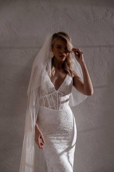 Bride in a lace V-neck gown with veil.