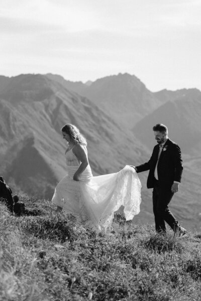 Groom carrying bride's dress train on wedding day in PNW mountains
