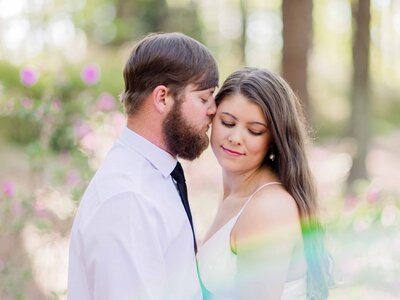 Bride and groom snuggling close with  a rainbow in front of them at Callaway Gardens  in Georgia.
