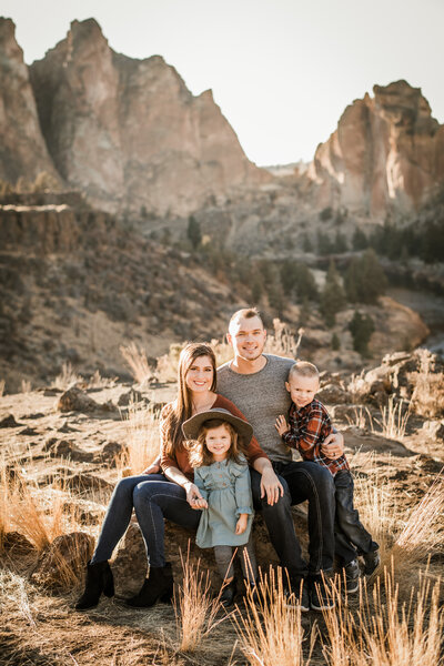 family of 4 sits and smiles