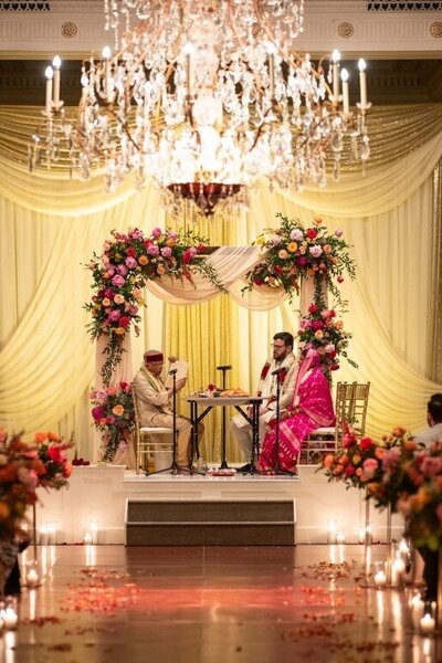 Close-up of Leigh Florist’s beautiful floral arrangements decorating a wedding ceremony arch with roses, eucalyptus, and hydrangeas for an outdoor venue.