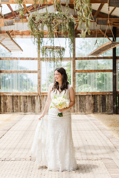 bride smiling in her wedding dress while holding a flower bouquet