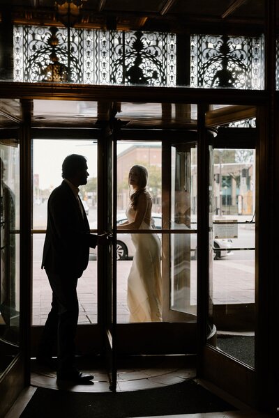 A wedding couple walking through a rotating door 