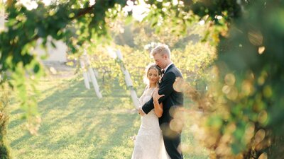 Bride and groom hold each other in a vineyard on a sunny day