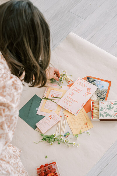 An over the shoulder view of McKenna arranging a flat lay representing her full service design offerings for wedding invitation suites.