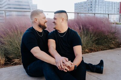 Nashville engagement photographer captures couples portraits of a gay couple holding hands and looking at each other during outdoor engagement session