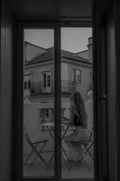 summer leigha photo sitting on a balcony in lisbon, portugal drinking a glass of wine while looking at the city views