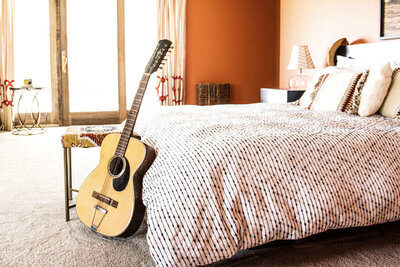 Location Branding photo bedroom guitar leaning against bed patio doors in background