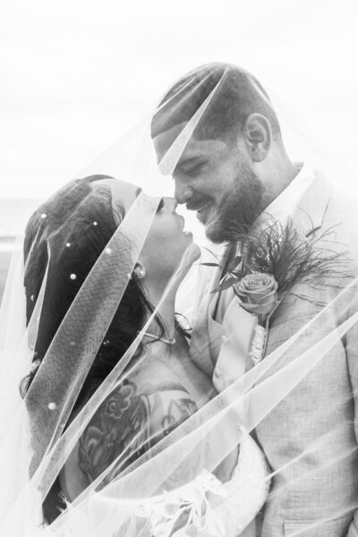 bride and groom about to kiss while wrapped in veil