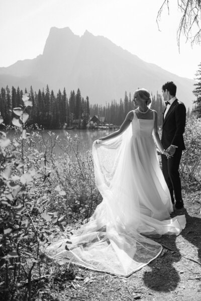 Bride and groom at Emerald Lake in Yoho National Park on a sunny summer day with turquoise water and Emerald Lake Lodge in the background captured as a romantic wedding portrait