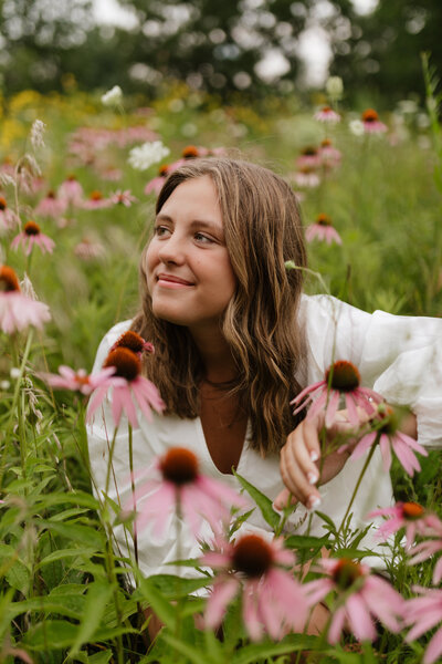 photo of high school girl sitting outside in a field of flowers for her Outdoor senior portraits Madison