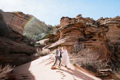 This eloping couple celebrates in a slot canyon. The groom picks his bride up off her feet and swings her around.