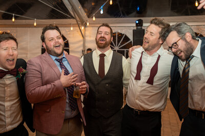 The groom from the wedding is  singing a song with his groomsmen.