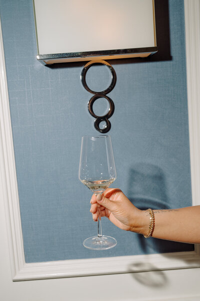 Elegant hand holding wine glass against artistic wall decor