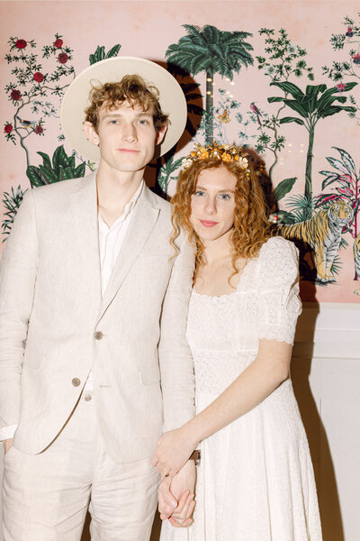 A modern wedding couple standing in front of the art-forward mural inside Common House Richmond. Their light, neutral outfits complement the clean, contemporary design of the venue, creating an elevated and intimate portrait that reflects the modern aesthetic of Common House weddings and Richmond wedding venues.
