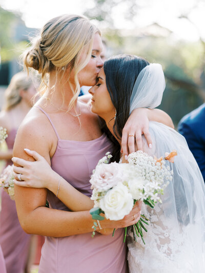 Bridesmaid kissing bride on the forehead