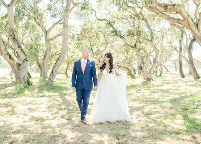 wedding couple holding hands under moss trees as their wedding in florida. 