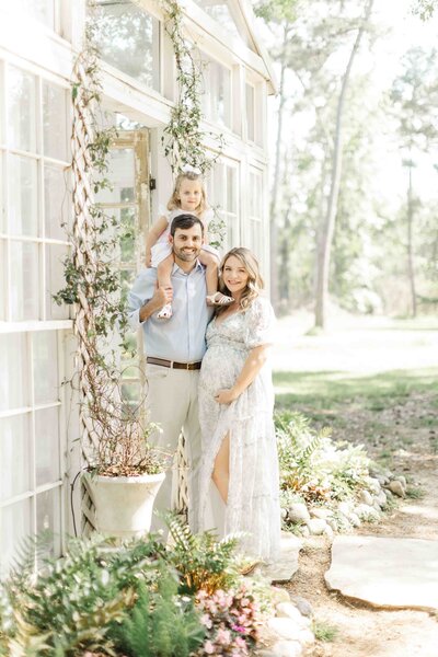 family of three smiling at camera for a maternity photo session