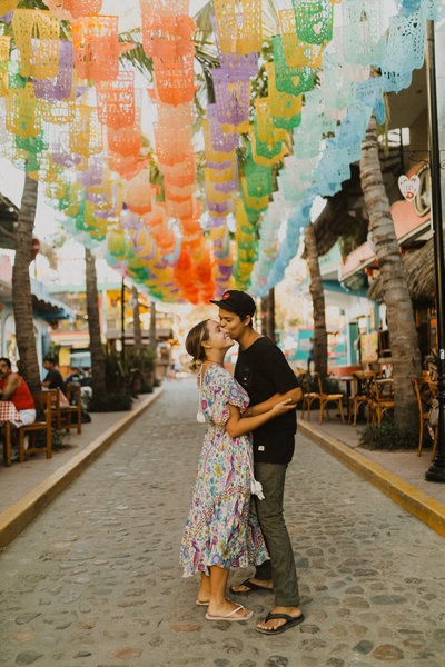 man kissing woman's cheek standing in street