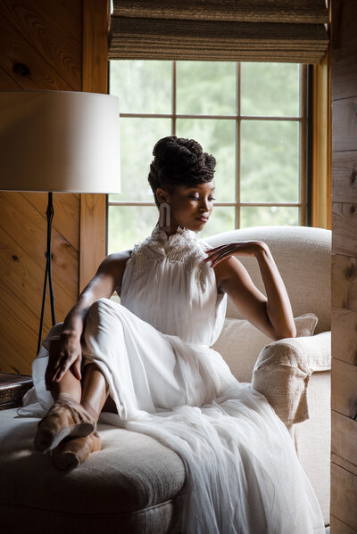 Black-bride-in-ballet-shoes-posing-gracefully-seated-on-a-beige-chair-at-North-Corner-Haven-in-South-Carolina