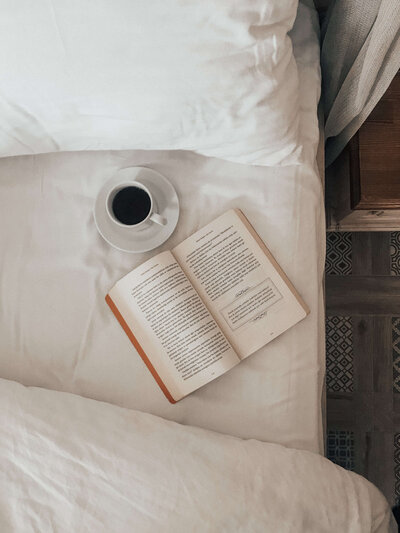 Coffee and open book on bed.