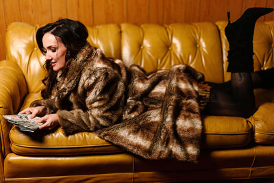 Photo of Juliet Trnka from the Brand Photoshoot-on a mustard yellow couch in a fur coat