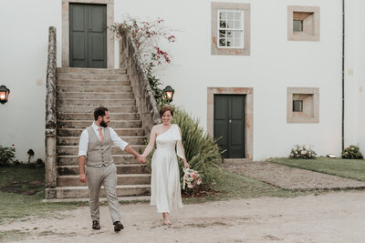 Bride & Groom walking hand in hand in front of the steps of Casa Grande de Fontao at their wedding in Portugal