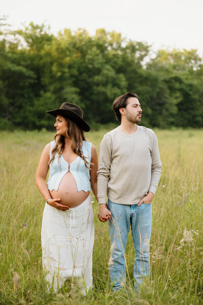 man and woman hugging each other and holding woman's belly for maternity shoot
