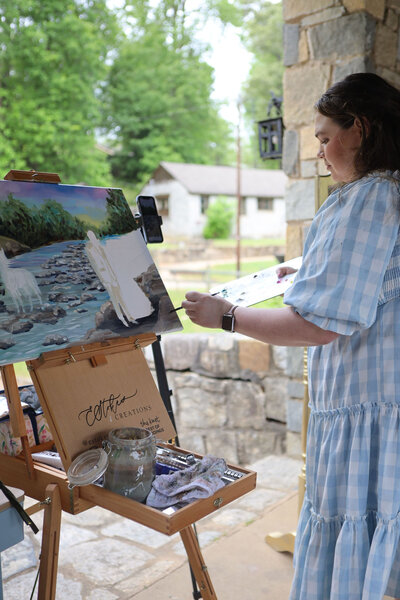 Artist Elyse Stokes painting live at a wedding, capturing a fairytale scene with an African American bride and white horse