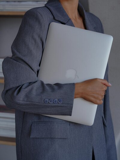 woman in a blue blazer holding her macbook