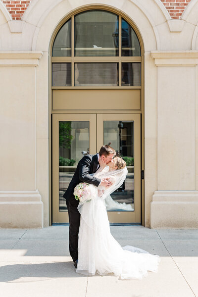 groom kissing bride in front of church doors