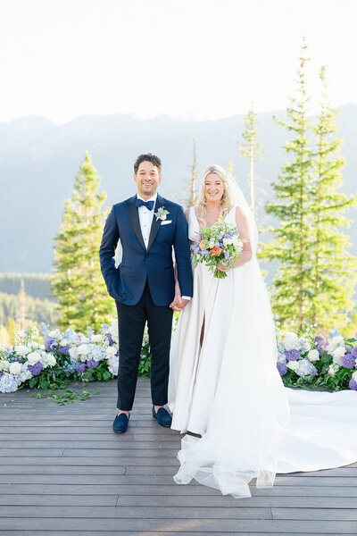 Newlyweds standing on top of Aspen Moutain holding hands