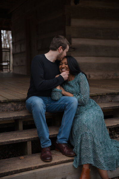 A couple sitting on wooden steps of a rustic cabin, enjoying a quiet, loving moment at Red Top Mountain.