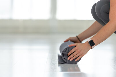 Erika Belanger unrolling puple yoga mat at Embrace Yoga Studio