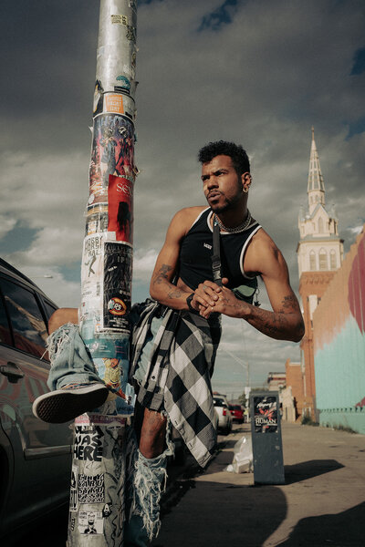 person wraps leg around streetlight pole during Denver city photoshoot