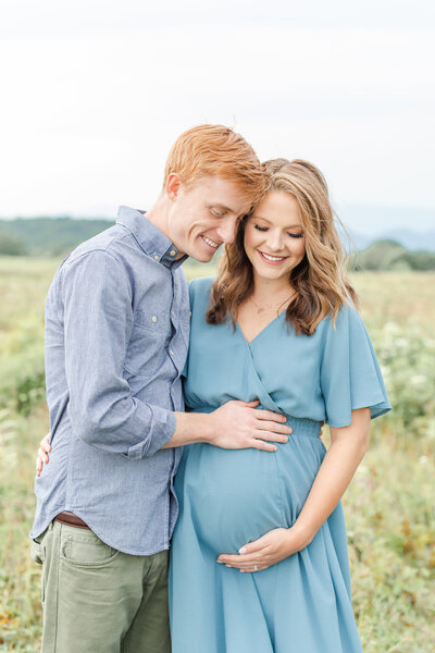 A couple admiring their baby bump and smiling down together by Northern Virginia Maternity Photographer