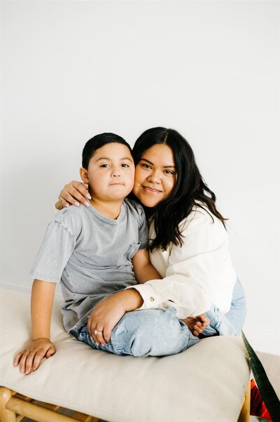 Virginia wedding photographer poses with her son as he sits on a table and she wraps her arms around him