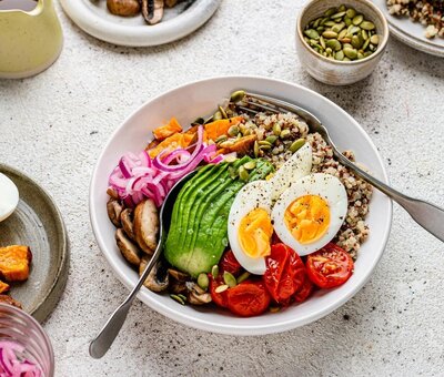 Colourful abundance bowl with quinoa, avocado, egg, roasted veg and pickled onions