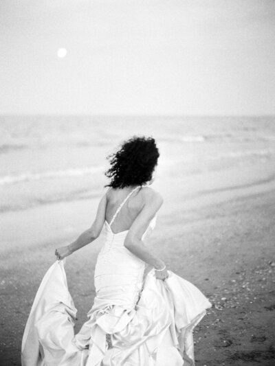 Bride runs down the beach in her wedding gown