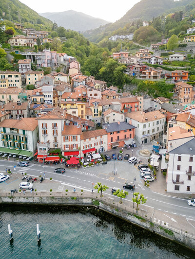 old historic buildings next to a busy street and water with mountains in the background